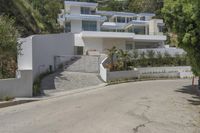 a street that runs up to a home with a white building on top and two stairs going up the side