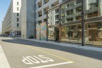 a paved street next to a building with glass windows with a logo on the side