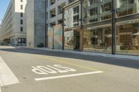 a paved street next to a building with glass windows with a logo on the side