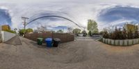 a fisheye lens photograph of trash cans and wires in an alleyway off a residential street