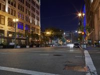 a city street is empty in the evening time at night with lights strung over and down