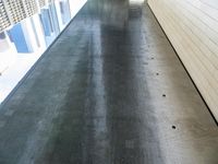 a wet walkway with water on it in a building with some large windows on the side of it