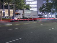 a truck driving down a city street in the night time at twilight with other cars and trees