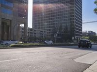 cars passing in front of an intersection of two large buildings and a sky line in the distance