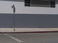 there is a stop sign at the curb outside a building with no one inside it