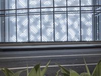 a building has a glass front in a city street, with greenery in front