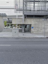 a bus is approaching a bus stop near a building and road side entrance entrance into a subway