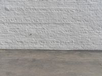 a fire hydrant in front of a brick wall next to a concrete floor with a wall that has some spots and lines on it