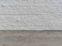 a fire hydrant in front of a brick wall next to a concrete floor with a wall that has some spots and lines on it