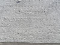 a fire hydrant in front of a brick wall next to a concrete floor with a wall that has some spots and lines on it