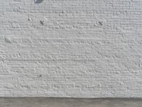 a fire hydrant in front of a brick wall next to a concrete floor with a wall that has some spots and lines on it