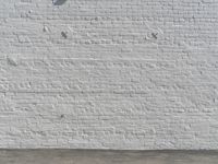 a fire hydrant in front of a brick wall next to a concrete floor with a wall that has some spots and lines on it