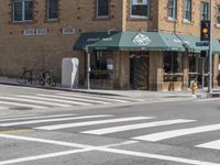 two people crossing a street in front of buildings and bikes parked at the curb line