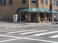 two people crossing a street in front of buildings and bikes parked at the curb line