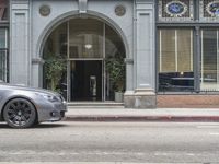 a parked sports car is in front of a building on a street corner with an arched window behind it