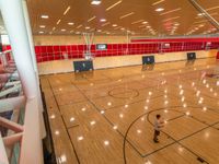 men and a woman playing basketball in a gym hall with red tiles on the walls