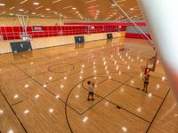 men and a woman playing basketball in a gym hall with red tiles on the walls