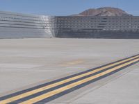 a yellow line on the runway at an airport, leading to a structure behind it