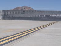 a yellow line on the runway at an airport, leading to a structure behind it