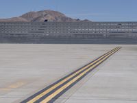 a yellow line on the runway at an airport, leading to a structure behind it