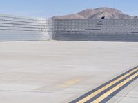 two lanes of cement with yellow stripe next to cement walls and a plane taking off