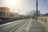 an empty highway with power lines leading to city buildings in the back ground and road tracks