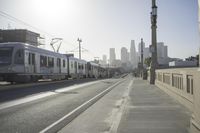 an empty highway with power lines leading to city buildings in the back ground and road tracks