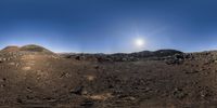 a sunlit sky is shining behind the rocks and dirt covered hills in a barren area