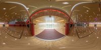 a ballerina sitting on a wooden floor with circular mirrors in the ceiling and the door to an indoor court