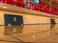 a gymnasium with hardwood flooring and large screen televisions in the middle of the gym