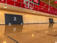 a gymnasium with hardwood flooring and large screen televisions in the middle of the gym