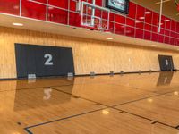 a gymnasium with hardwood flooring and large screen televisions in the middle of the gym