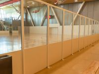 a line of benches inside a sports center next to a glass wall and ceiling filled with windows