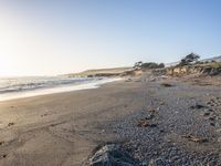 a grassy field by the shore and a cliff with rocks in the ocean in the background