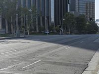 a person walking down a deserted city street with skyscrapers in the background in the daytime