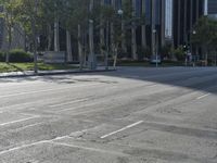 a person walking down a deserted city street with skyscrapers in the background in the daytime