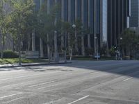 a person walking down a deserted city street with skyscrapers in the background in the daytime