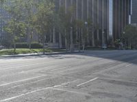 a person walking down a deserted city street with skyscrapers in the background in the daytime