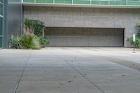 a large empty area with trees and grass growing outside of the building, including a bench in front of an entrance to the space