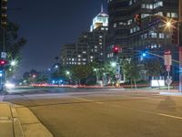 street lights, an intersection and multiple high rise buildings lit up at night in a city