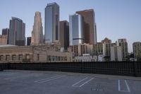 a parking lot has two parking meter and two red telephone booths in it, the city behind it