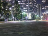 the street is lined with cars and tall buildings near each other at night time,