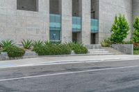 a white motorcycle is parked near the curb near a building with steps and plants on one side