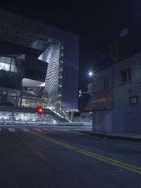 a stop light shines next to the side of a building in a city at night