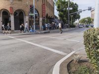 the pedestrians are waiting at the green traffic light to cross the street from the shops