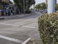 the pedestrians are waiting at the green traffic light to cross the street from the shops