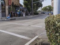 the pedestrians are waiting at the green traffic light to cross the street from the shops