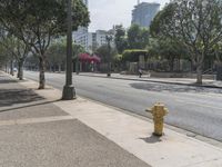 a yellow fire hydrant next to an empty sidewalk on a sunny day in a city