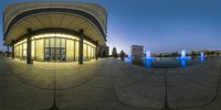 a view of a fountain, clock and building in the evening time outside an opera