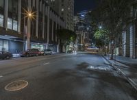 a city street with cars, buildings and other street signs lit up at night from the ground